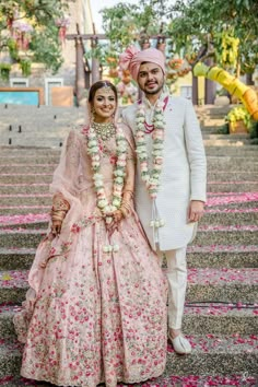 two people standing next to each other in front of some stairs with flowers on them