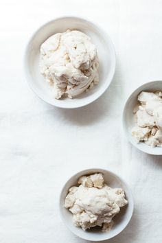 three bowls filled with food sitting on top of a white tablecloth next to each other