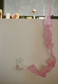 a pink streamer hanging from the side of a wall next to a light switch