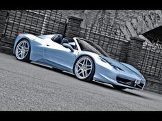 a blue sports car parked in front of a brick wall