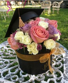 a graduation hat with flowers in it sits on a table outside at a park or lawn