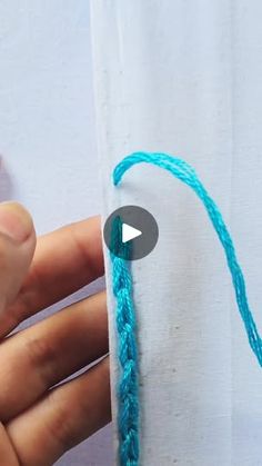 someone is stitching the end of a piece of fabric with blue yarn on it