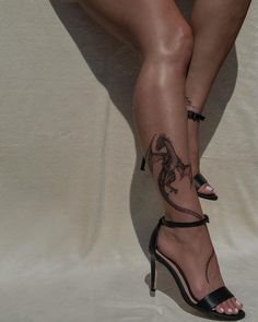 a woman's legs with tattoos on them and her leg in high heel sandals