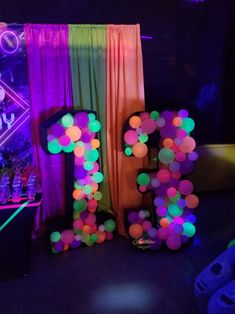 the letters p and f are lit up in neon colors, with balloons floating from them