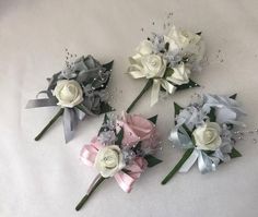 four different colored flowers are arranged on a white tablecloth with pearls and beads around them