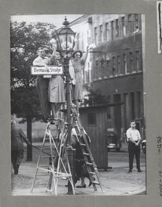 an old black and white photo of three people standing on top of a lamp post