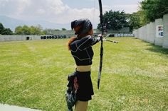 a woman is practicing her archery skills on the grass