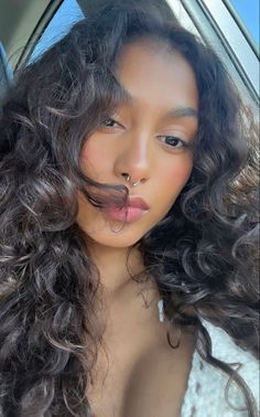 a woman with long curly hair sticking her tongue out from behind a car door window