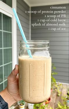 a person holding a mason jar with a straw in it and text overlay that reads, cinnamon i scoop of protein powder into a cup of pb