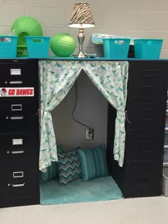 an office cubicle with drawers and curtains on the top shelf is decorated in blue and green