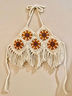 a crocheted bag hanging on the wall with tassels and sunflowers