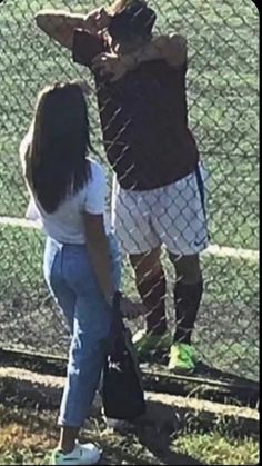 two people standing next to each other in front of a chain link fence with the words,