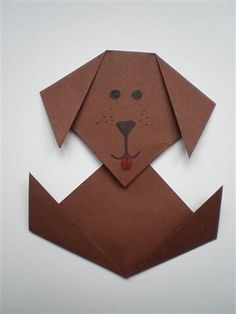 an origami dog head on top of a piece of brown paper that is folded in half