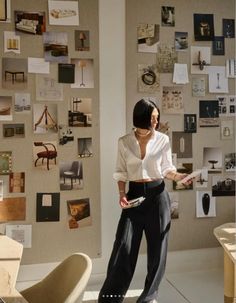 a woman standing in front of a wall with pictures on it