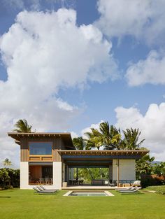 the house is surrounded by lush green grass and palm trees, as well as a swimming pool