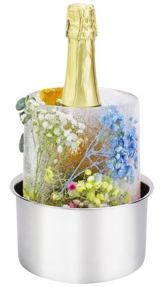 a bottle of champagne in a metal container with flowers and plants on the bottom,