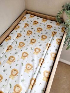 a baby's crib with a monkey print on it and a plant in the corner