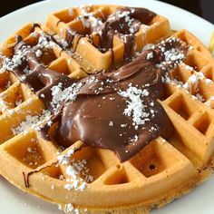 a white plate topped with waffles covered in chocolate