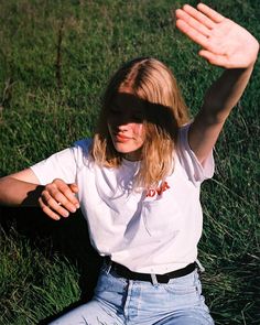 a woman laying in the grass with her hands behind her head and wearing a blindfold