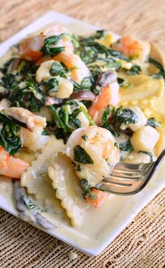 a plate with shrimp, spinach and pasta on it is being eaten by a fork