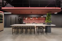 a large kitchen and dining area in an office building with red lighting on the ceiling