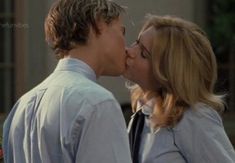 a man and woman kissing each other in front of a building with flowers on the ground