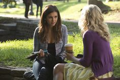 two women sitting on the ground talking to each other