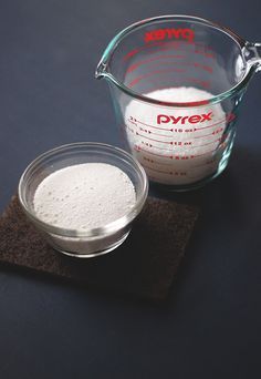 a measuring cup filled with white powder on top of a brown cloth next to a glass container