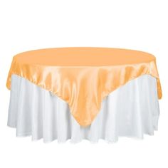 an orange and white table cloth on top of a round table with a white skirt