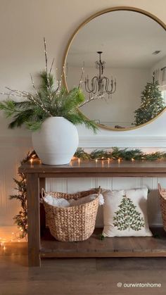 a christmas entryway decorated with greenery, pine cones and white baskets under a round mirror