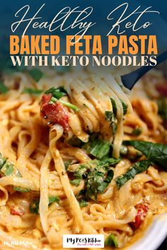 a spoonful of pasta with spinach and tomatoes is being lifted from the bowl