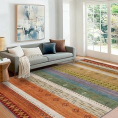 a living room filled with lots of furniture and rugs on top of a hard wood floor