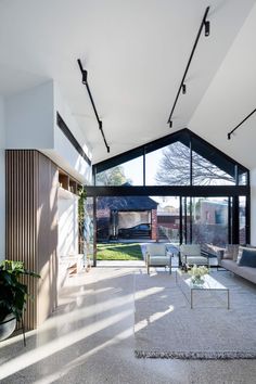 an open living room with lots of furniture and large glass windows on the side of it