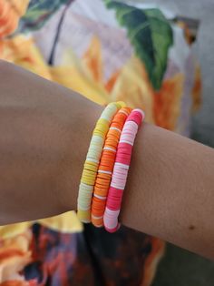 a woman wearing three different colored bracelets on her arm