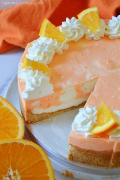 an orange cheesecake on a white plate next to sliced oranges