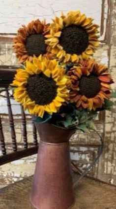 a vase filled with lots of sunflowers on top of a wooden table next to a chair