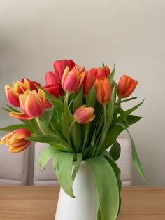 a white vase filled with orange and red flowers