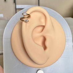 a pair of gold ear rings sitting on top of a plastic object in front of a couch