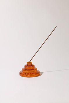 an orange object with a wooden stick sticking out of it's center on a white surface