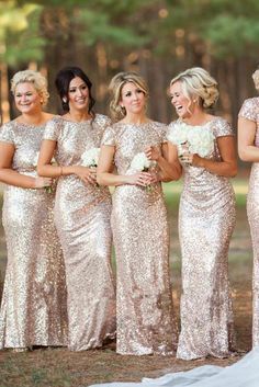 a group of women standing next to each other in front of some trees and grass