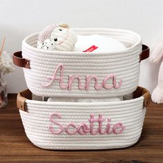 two white baskets with pink letters and a teddy bear in the middle one is personalized