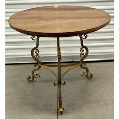 a round wooden table sitting on top of a cement floor next to a garage door