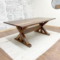 a wooden table sitting on top of a white rug in front of a brick wall