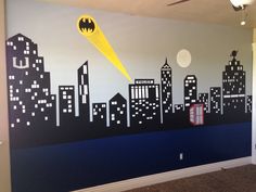 a batman themed bedroom with the city skyline painted on it's wall and a yellow bat flying through the sky