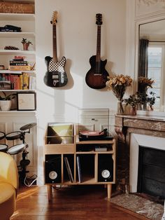 two guitars are hanging on the wall above a record player's desk in a living room