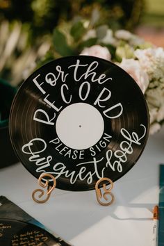 a record sitting on top of a table next to some flowers and an open book