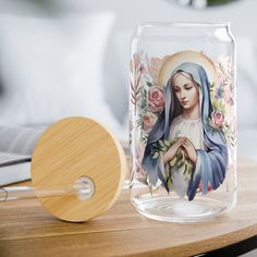 a glass jar with a painting of the virgin mary on it next to a wooden paddle