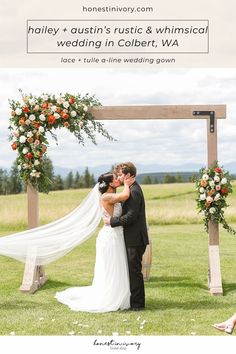 a bride and groom kissing under an arch decorated with flowers in front of the wedding ceremony sign