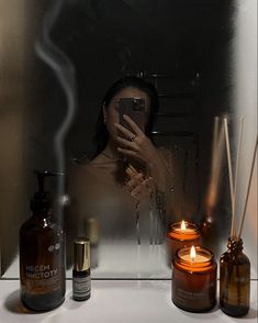 a woman taking a selfie with her cell phone and candles in front of her