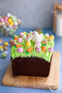 a chocolate cake with green frosting and easter decorations on top, sitting on a cutting board